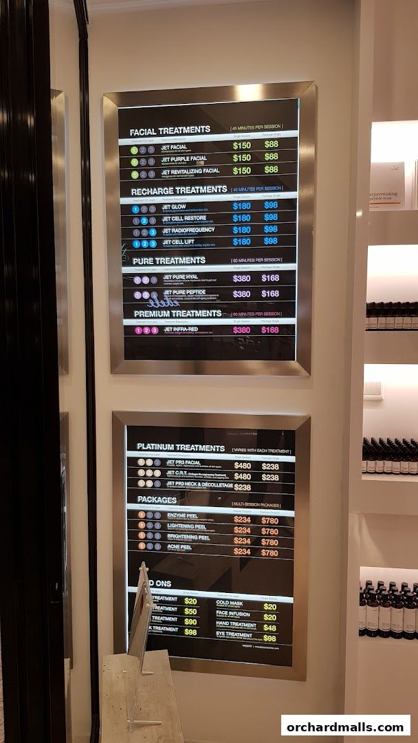 A digital menu board displaying various facial treatments, packages, and add-ons with prices.