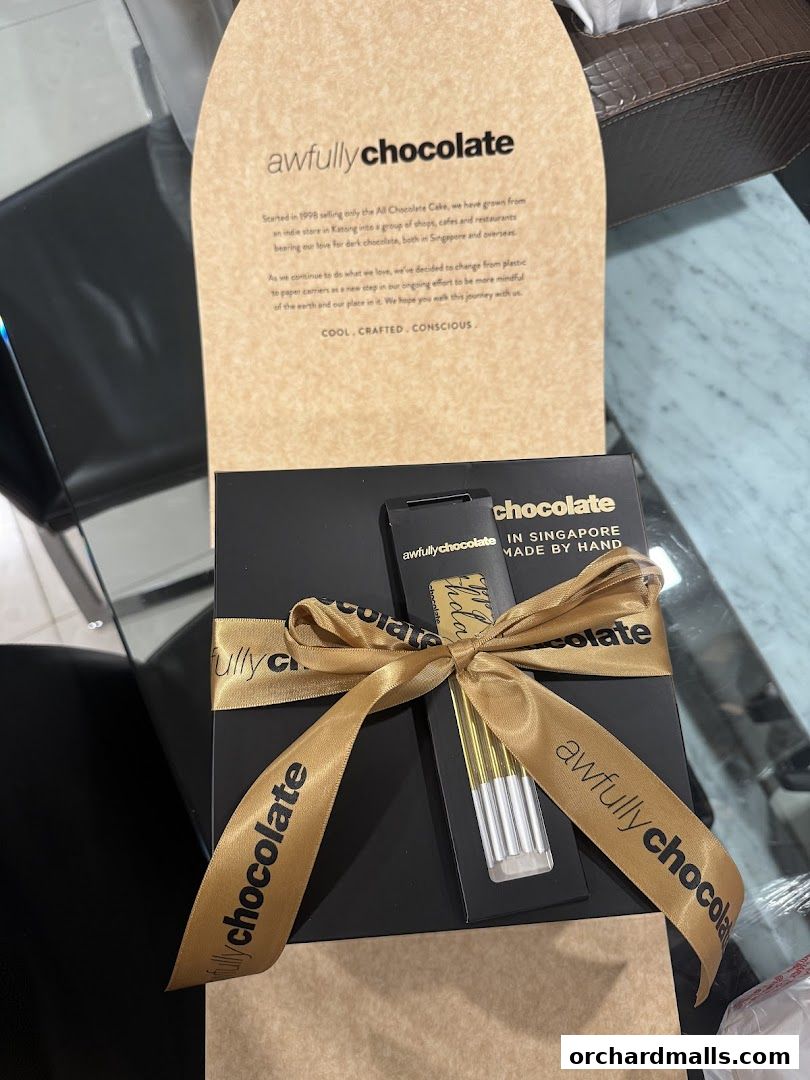 A beautifully packaged chocolate gift box from Awfully Chocolate, tied with a gold ribbon.