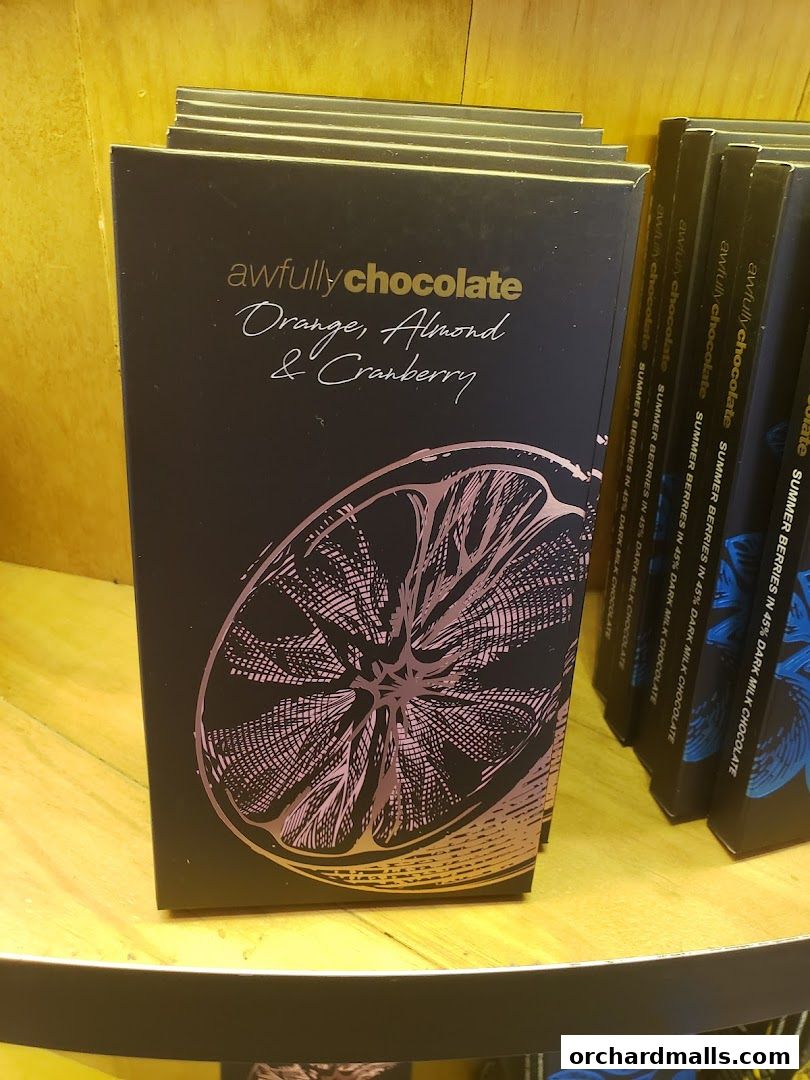 A stack of Awfully Chocolate boxes featuring orange, almond, and cranberry flavors.
