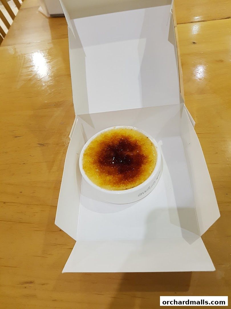 A crème brûlée dessert in a white box from Awfully Chocolate.