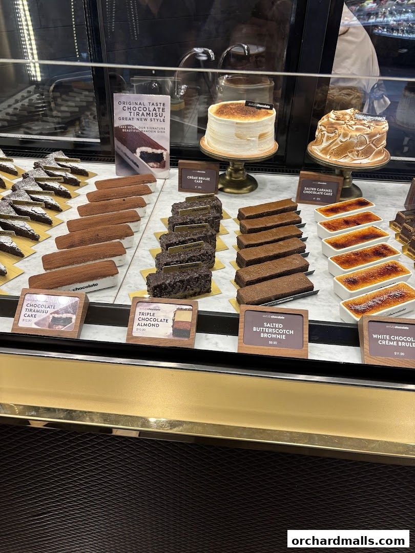 A display case filled with various chocolate cakes, brownies, and crème brûlée desserts.
