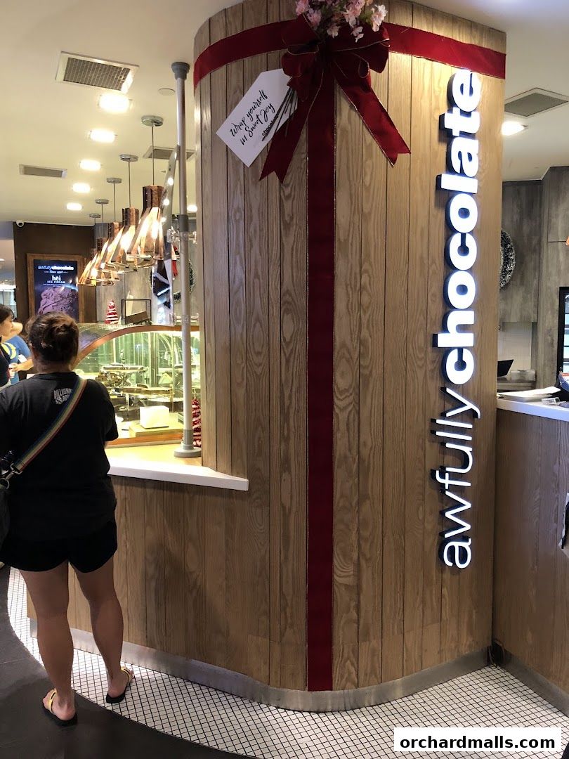 A person stands at the counter of Awfully Chocolate, a bakery and cake shop.