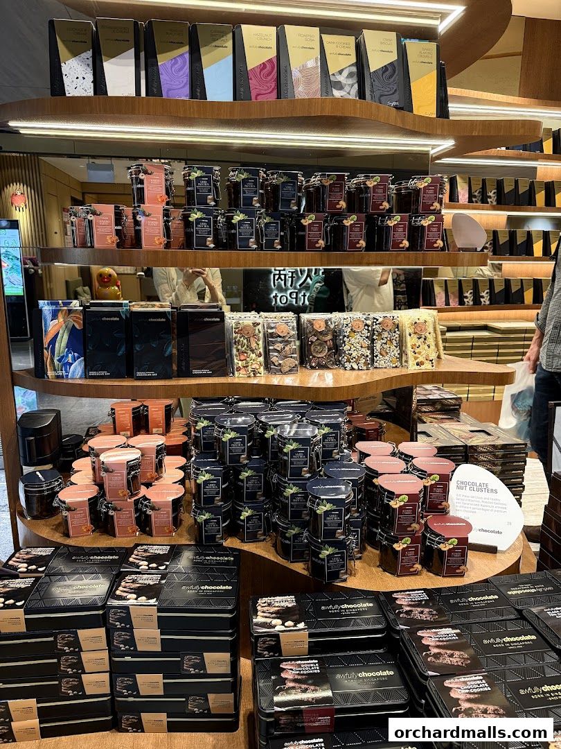 A display of various chocolate products and jars of treats on wooden shelves.