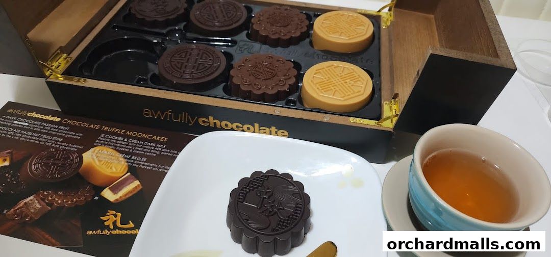 A box of Awfully Chocolate mooncakes with a cup of tea and a single mooncake on a plate.