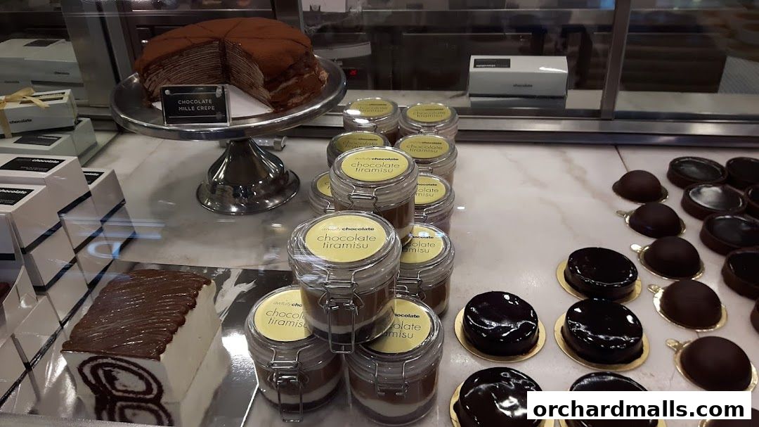 A display case filled with various chocolate desserts, including a mille crepe cake and individual tiramisu jars.