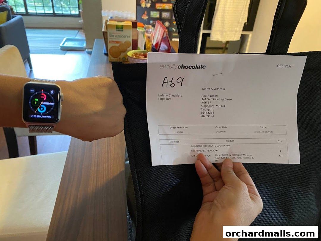 A person's wrist with a smartwatch and a delivery receipt from Awfully Chocolate.