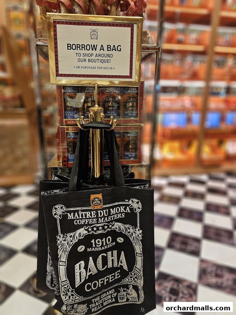 A Bacha Coffee tote bag displayed with a sign offering to borrow or purchase it.