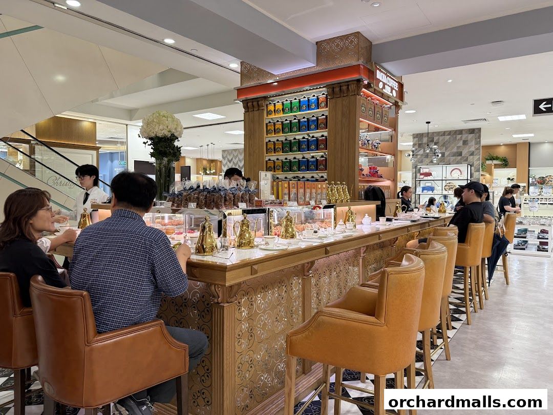 People seated at a coffee bar with colorful tea tins displayed on shelves.