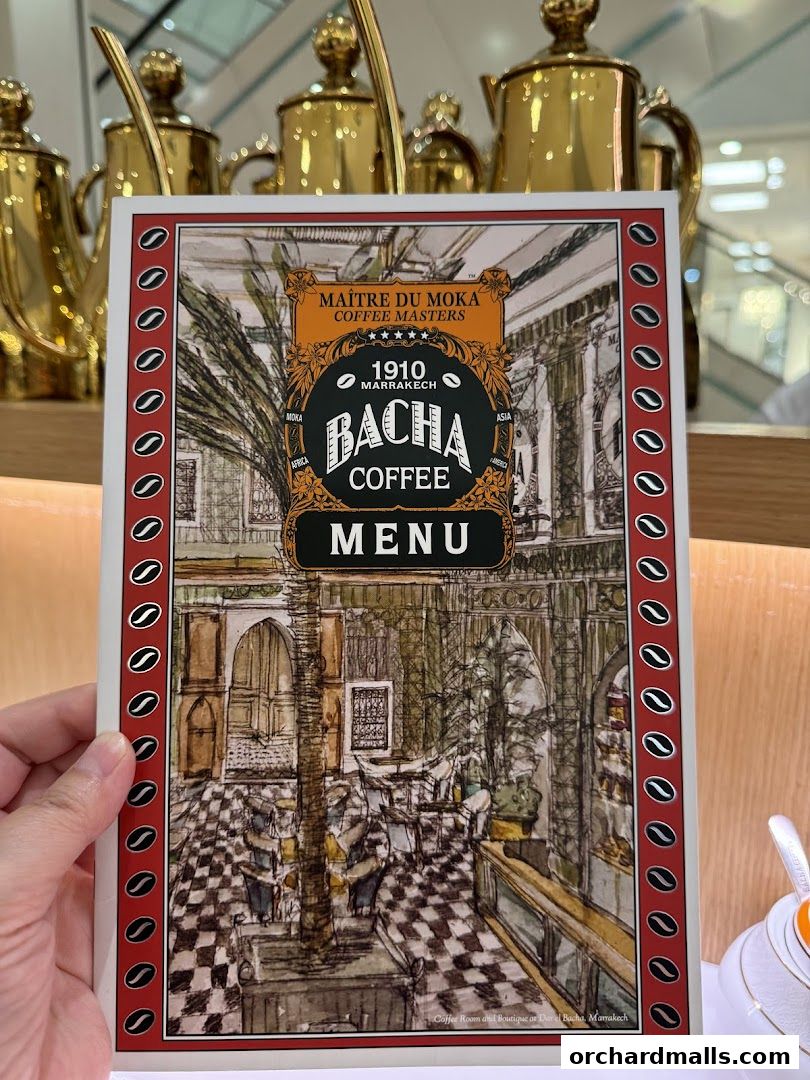A hand holds a Bacha Coffee menu featuring an artistic illustration of a coffee room.