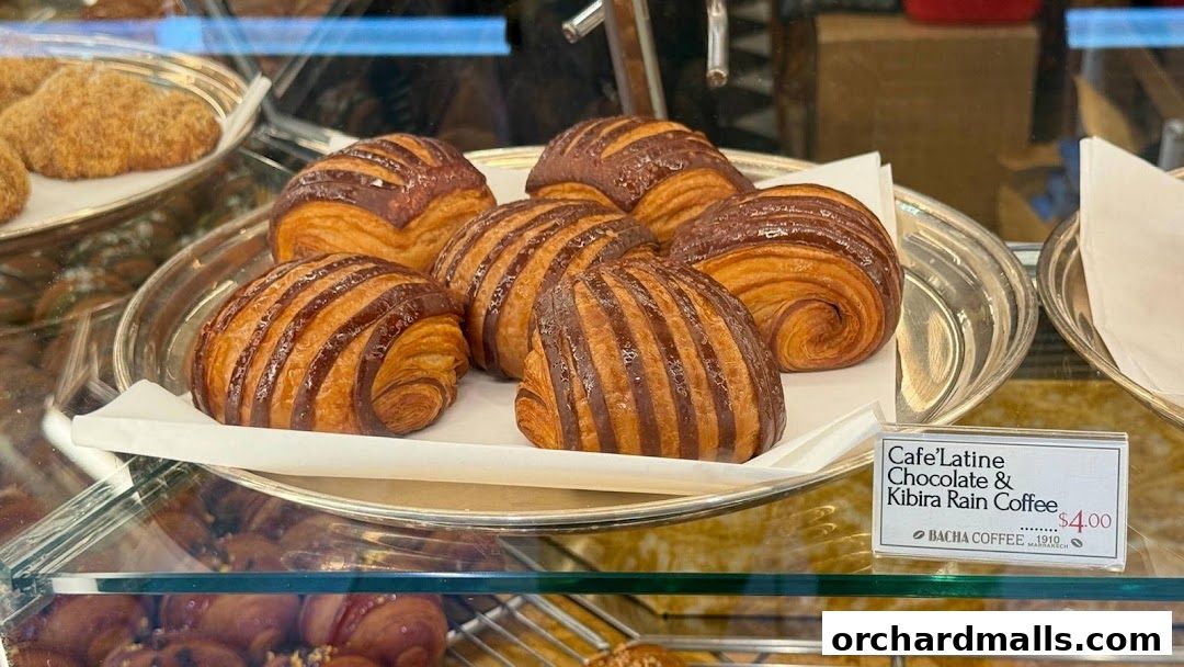 A display of freshly baked chocolate croissants and other pastries in a cafe window.