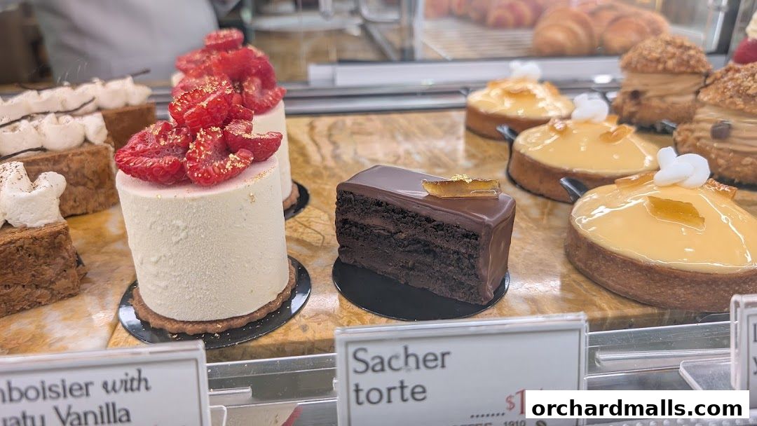 A display case filled with beautifully decorated cakes and pastries, including a Sacher torte.