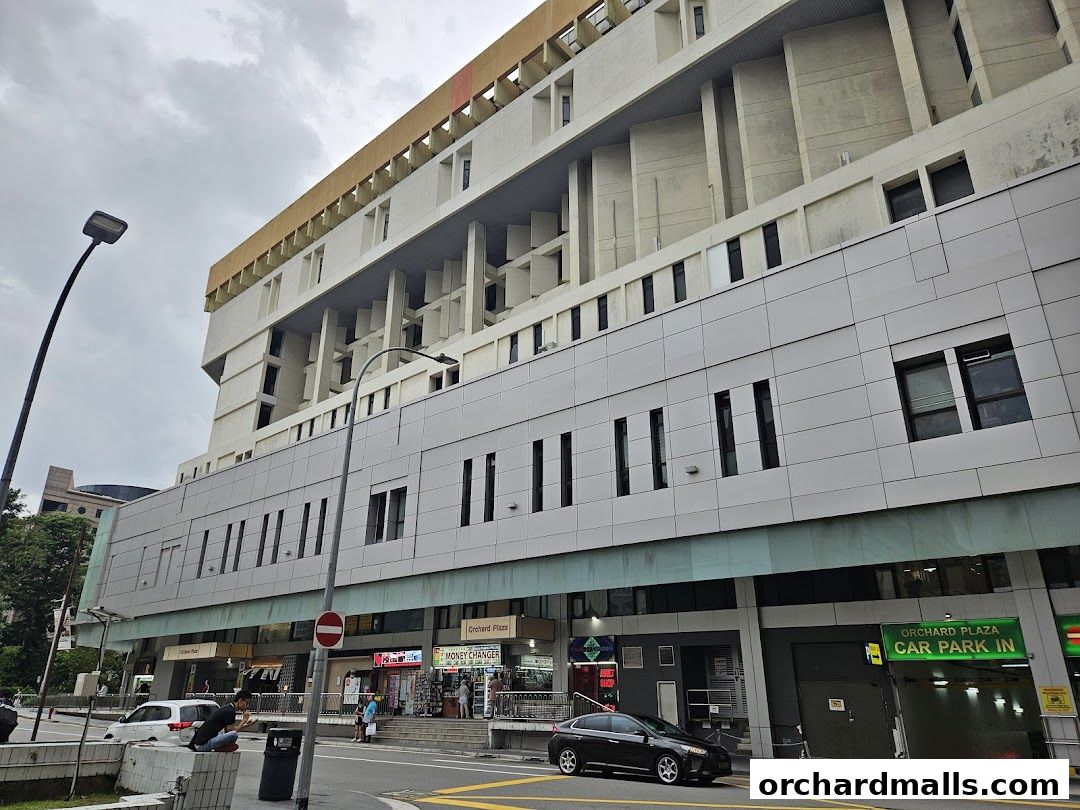 Exterior view of Orchard Plaza building with shops and a car park entrance.