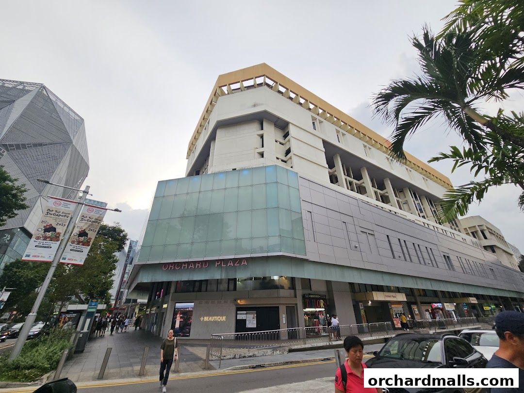 Exterior view of Orchard Plaza shopping mall with shops and banners on a street.
