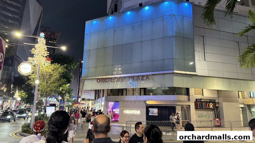 Orchard Plaza building facade at night with Christmas decorations and shoppers.