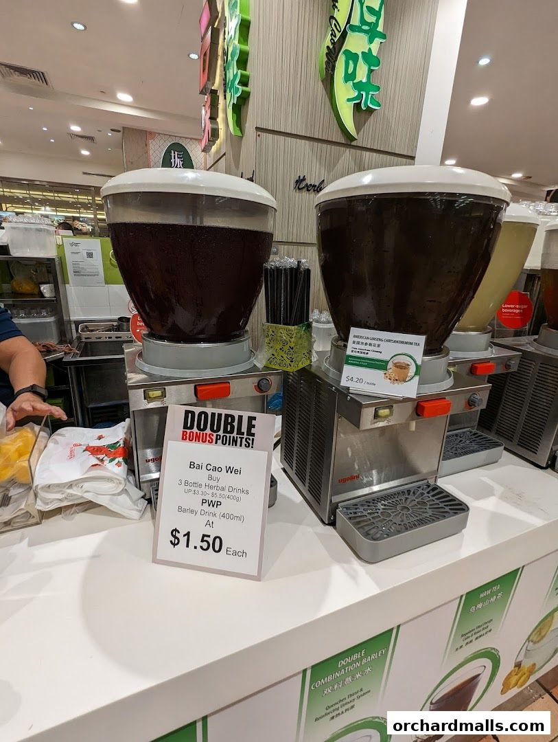 Bai Cao Wei shop display featuring large dispensers of herbal drinks and a promotional sign.