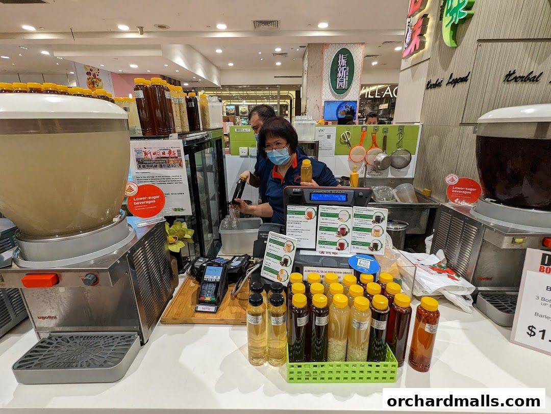 Staff serving beverages at a counter with large dispensers and bottled drinks.