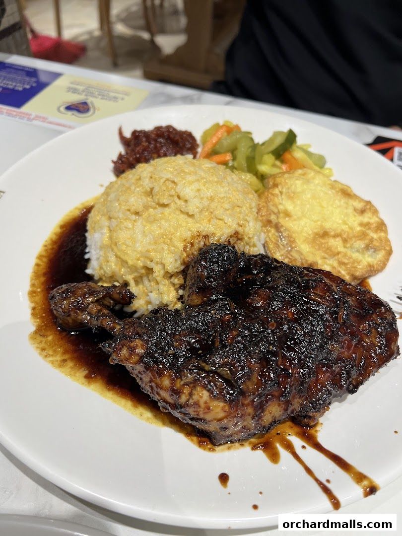 A plate of Indonesian BBQ chicken with rice, egg, and pickles.