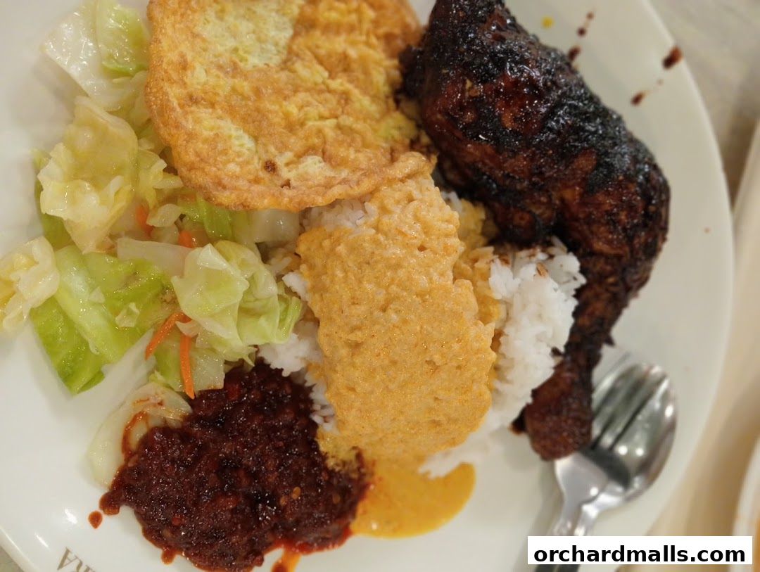 A plate of Indonesian BBQ chicken with rice, vegetables, and sambal.