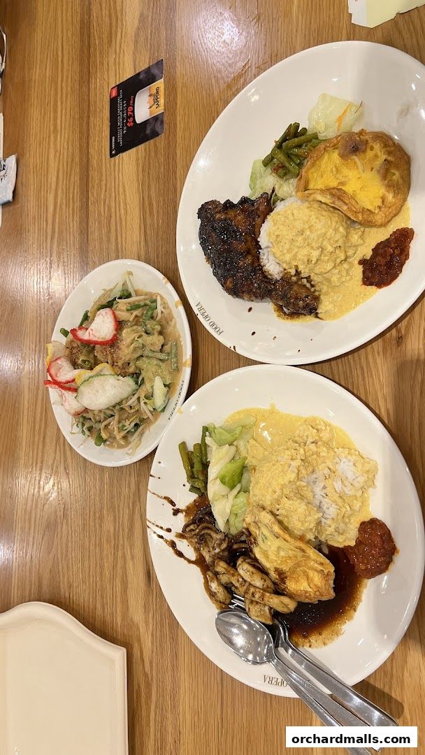 Two plates of Indonesian BBQ with rice, vegetables, and a side salad.
