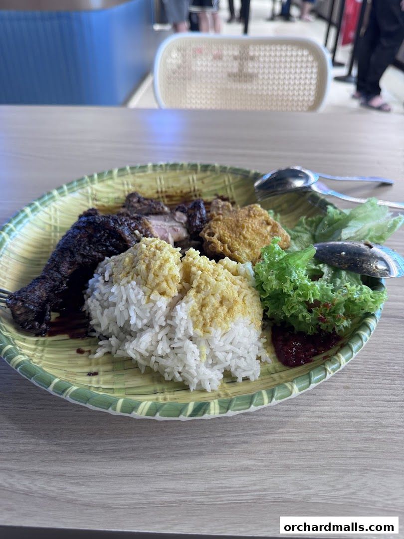 A plate of Indonesian BBQ with rice, meat, and salad on a wooden table.