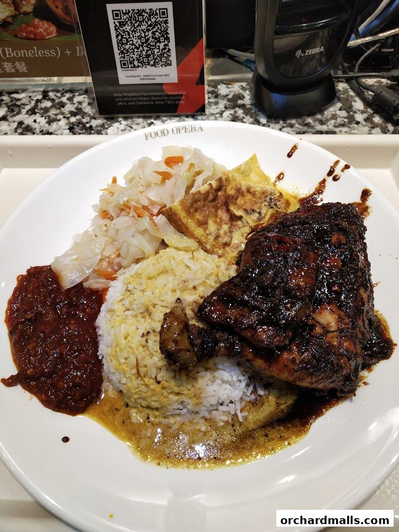 A plate of Indonesian BBQ chicken with rice, vegetables, and chili paste.