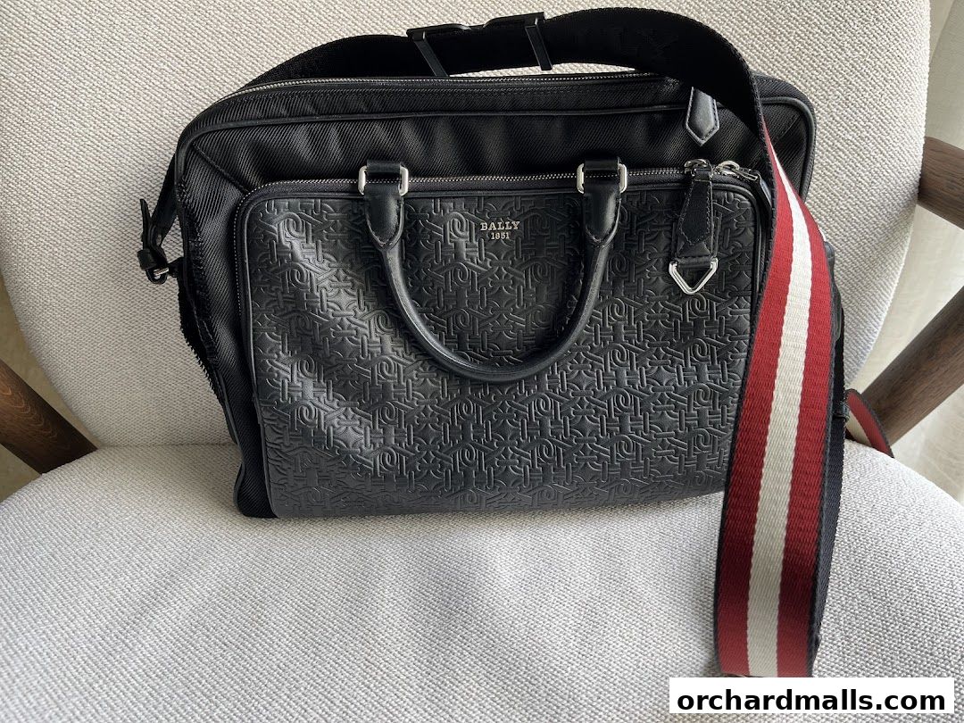A black Bally briefcase with embossed logo and signature red and white stripe strap.