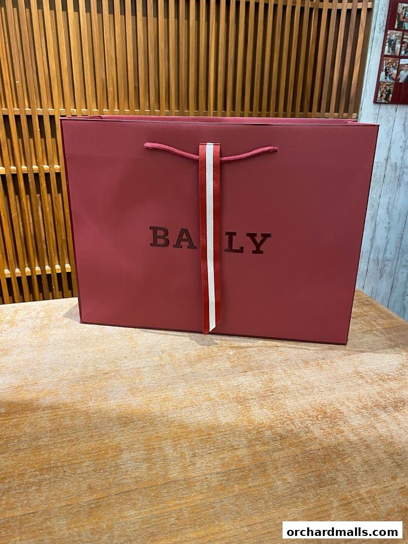 A red Bally shopping bag with the brand name prominently displayed.