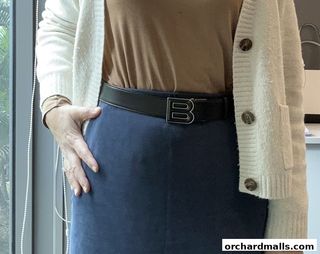A person wearing a Bally belt with a distinctive 'B' buckle, paired with a blue skirt and cardigan.