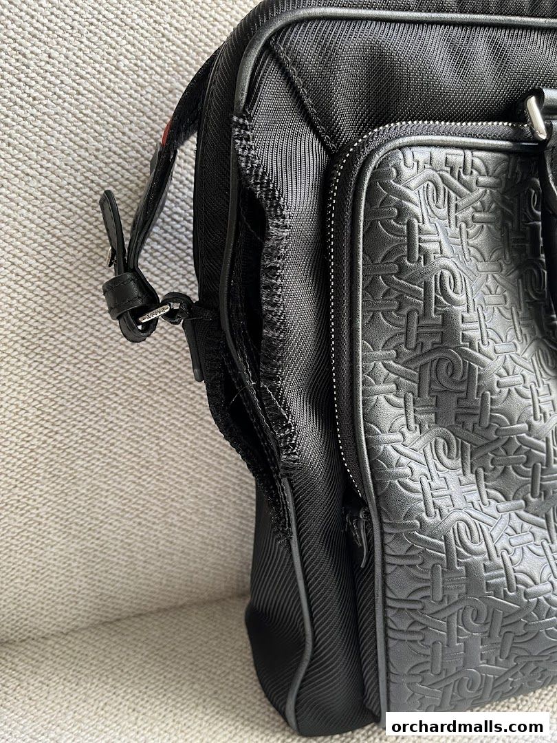 Close-up of a black Bally bag with embossed logo pattern and damaged zipper.