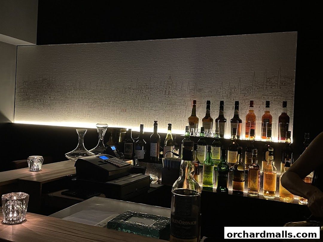 A dimly lit bar counter with a wide selection of liquor bottles displayed.