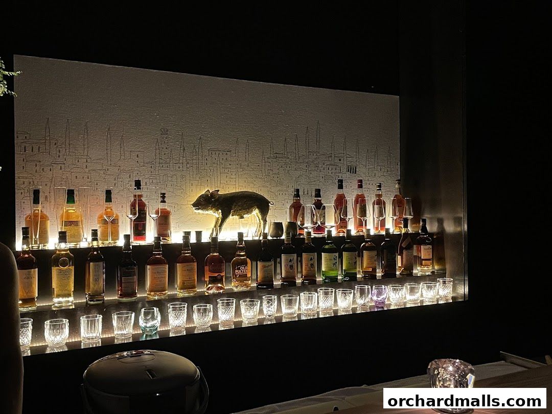A well-lit bar display featuring numerous bottles of liquor and glassware.