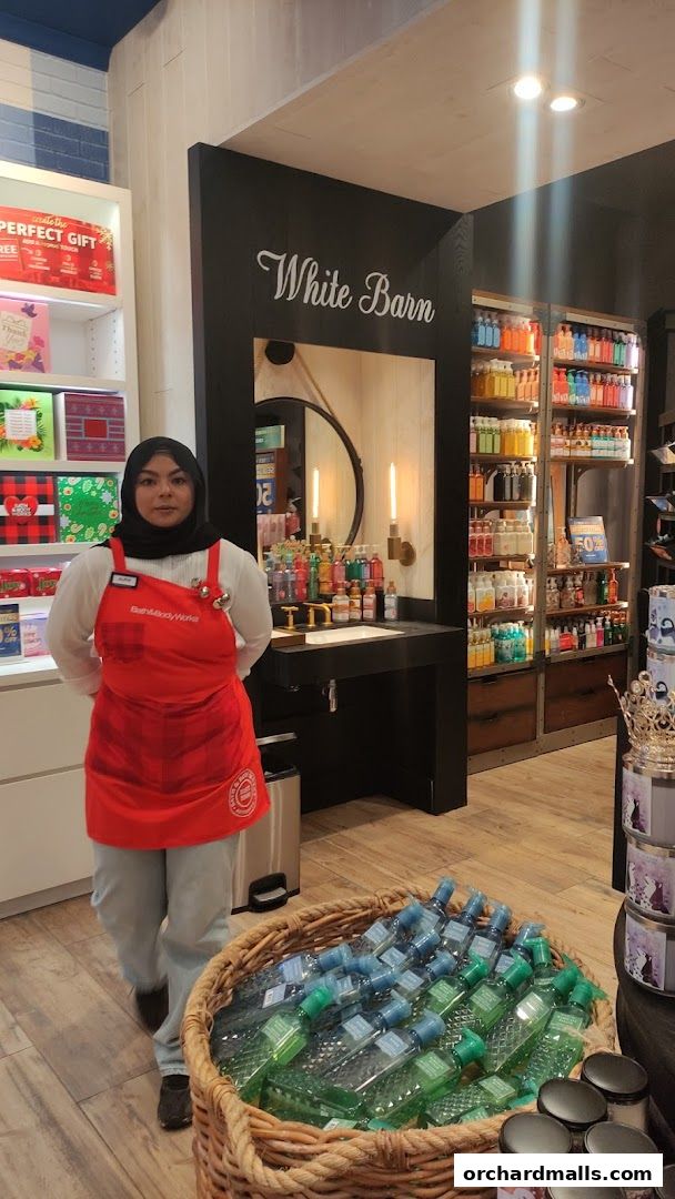 A store employee stands in front of shelves stocked with Bath & Body Works products.