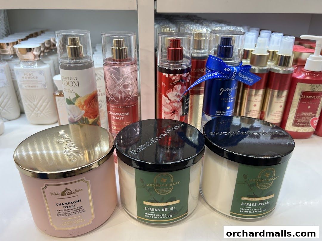 A display of Bath & Body Works candles and body sprays, featuring scents like Champagne Toast and Eucalyptus.