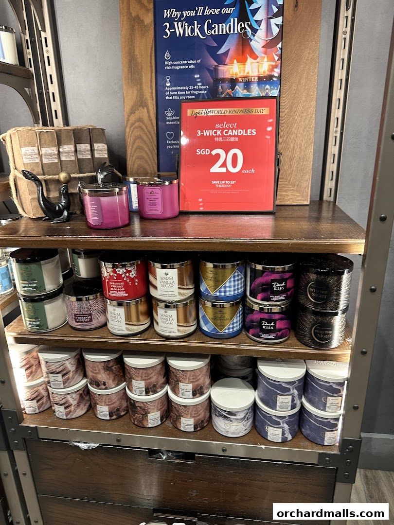 A display of Bath & Body Works 3-wick candles with a promotional sign.