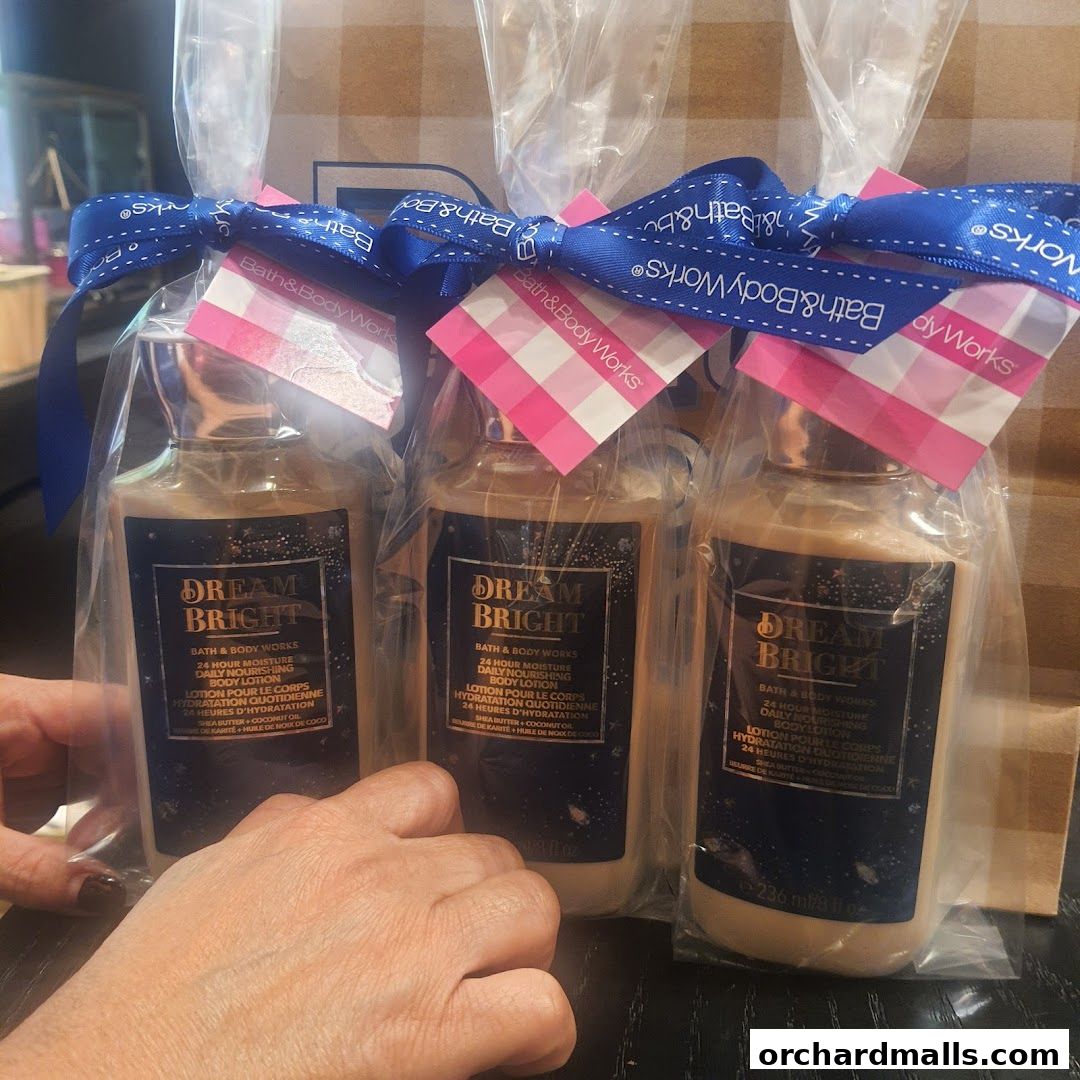 Three bottles of Bath & Body Works Dream Bright body lotion are displayed, tied with blue ribbon.