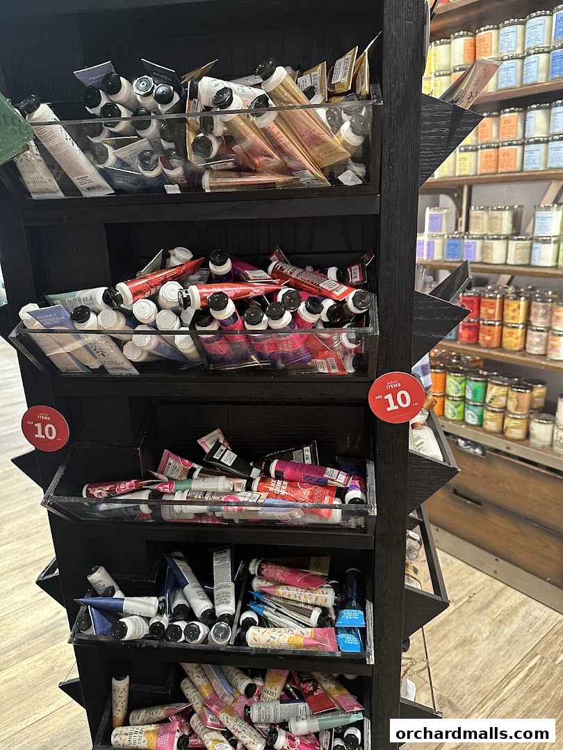 A display rack filled with various tubes of hand cream and lotions, with candles in the background.