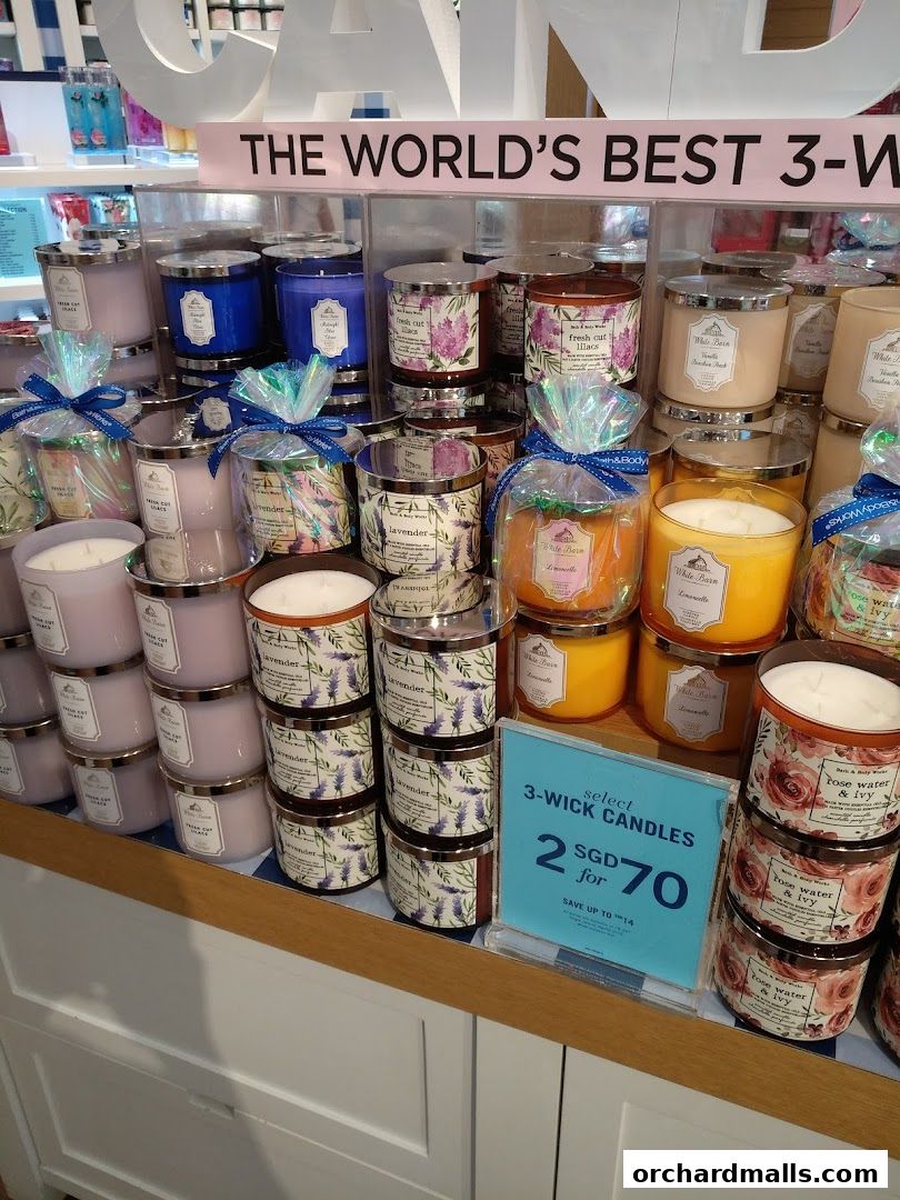 A display of Bath & Body Works 3-wick candles with a promotional sign.