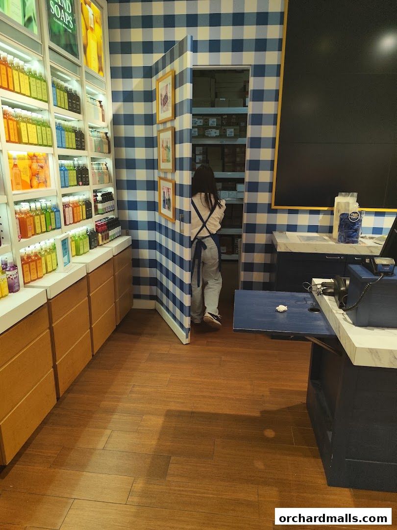 A person in an apron walks into a storage area of a Bath & Body Works store.