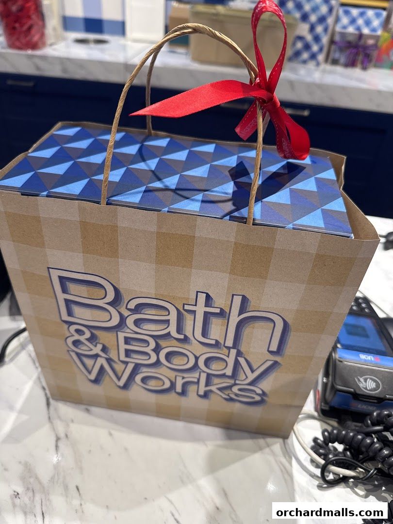 A Bath & Body Works shopping bag with a red ribbon and blue patterned contents.