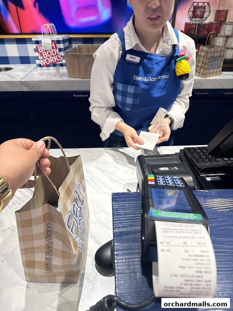 A customer is paying at the counter of Bath & Body Works with a shopping bag.