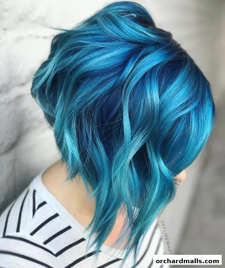 A person with vibrant blue and teal layered bob haircut with wavy texture.