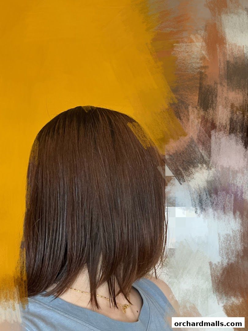 A person with sleek, dark brown hair against a vibrant yellow and abstract background.