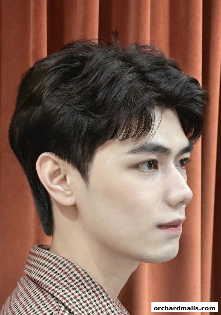 Close-up profile of a young man with styled dark hair and a checkered jacket.