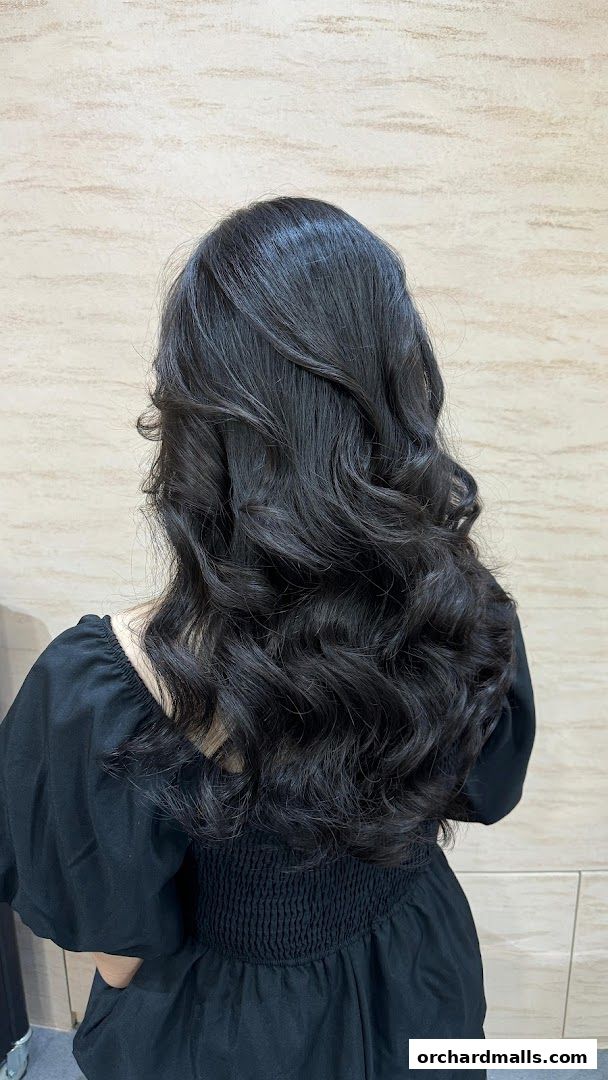 A person with voluminous, dark, wavy hair styled with curls.