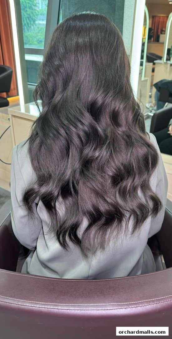 A person with long, wavy, dark hair styled in a salon.