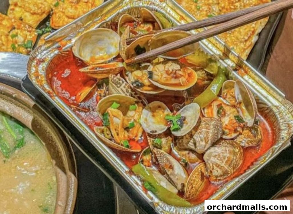 A close-up shot of a steaming dish of clams in a spicy red sauce with chopsticks.
