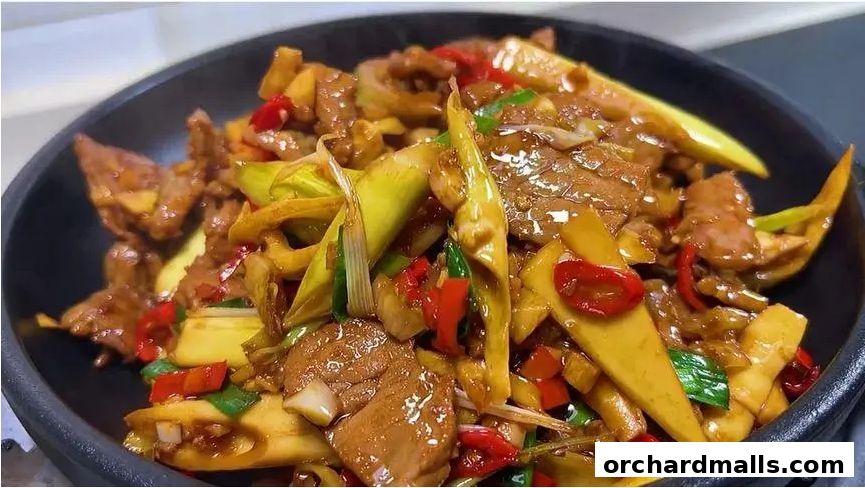 A close-up shot of a savory stir-fry dish with beef, bamboo shoots, and chili peppers.