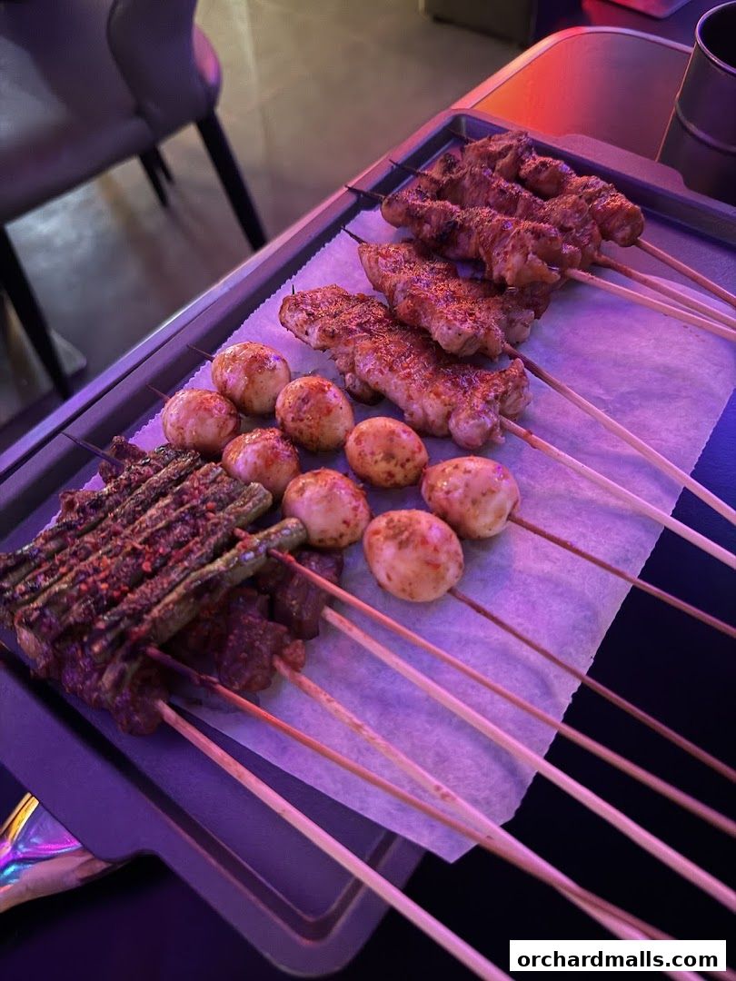 A tray of assorted grilled skewers, including meat, vegetables, and mushrooms, seasoned with spices.
