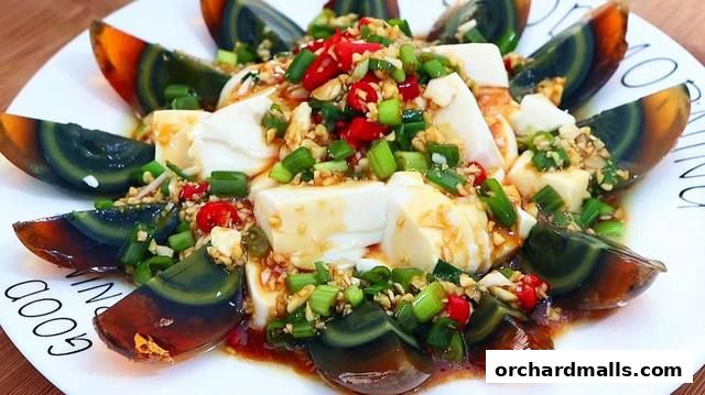 A plate of tofu and century eggs topped with chili, scallions, and garlic.