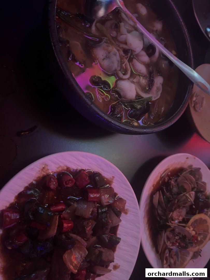 Three plates of food, including a stew with seafood, a stir-fry, and clams with lemon.